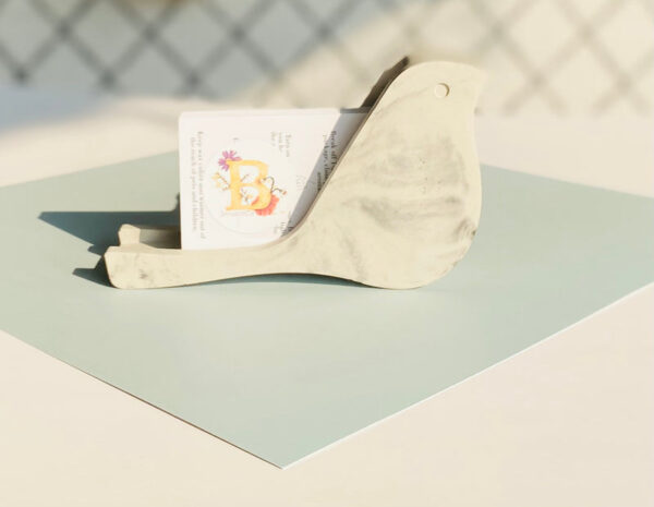Concrete decorative bird business card holder on modern desk – minimalist office decor, unique desk accessory, handmade bird-shaped card stand for aesthetic home office organization.