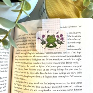 Cute kawaii frog sitting on a lily pad with flowers on a pink and white plaid background
